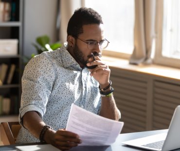 A man reviews documents at a desk, SB 1162 went into effect in California on January 1, 2023.
