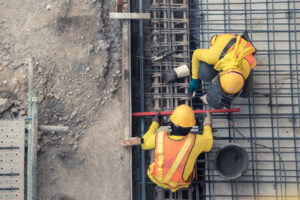 An aerial view of construction workers. Federal law requires certified payroll reports for government-funded projects.