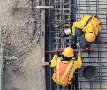 An aerial view of construction workers. Federal law requires certified payroll reports for government-funded projects.