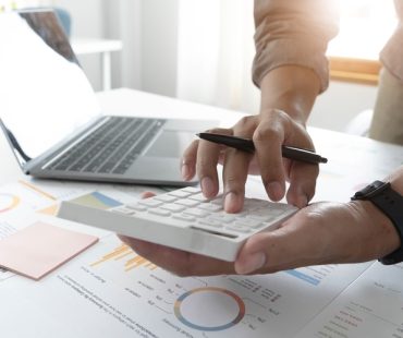 A small business owner types on a calculator, working on payroll.