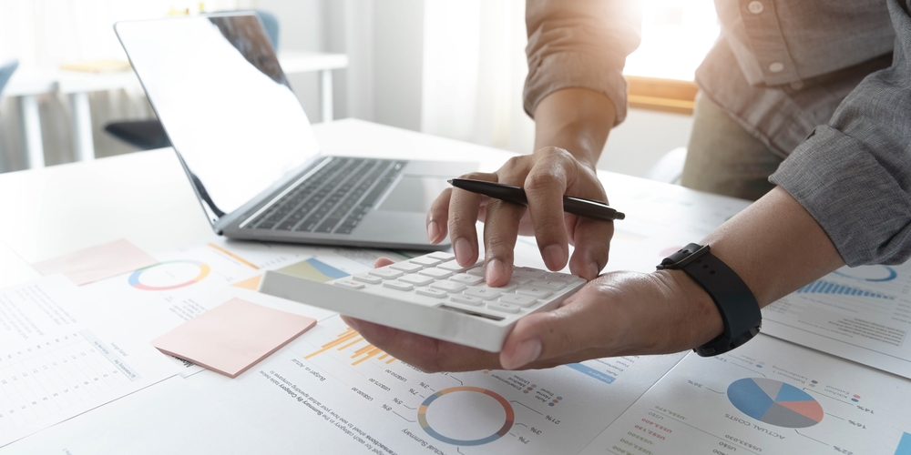 A small business owner types on a calculator, working on payroll.