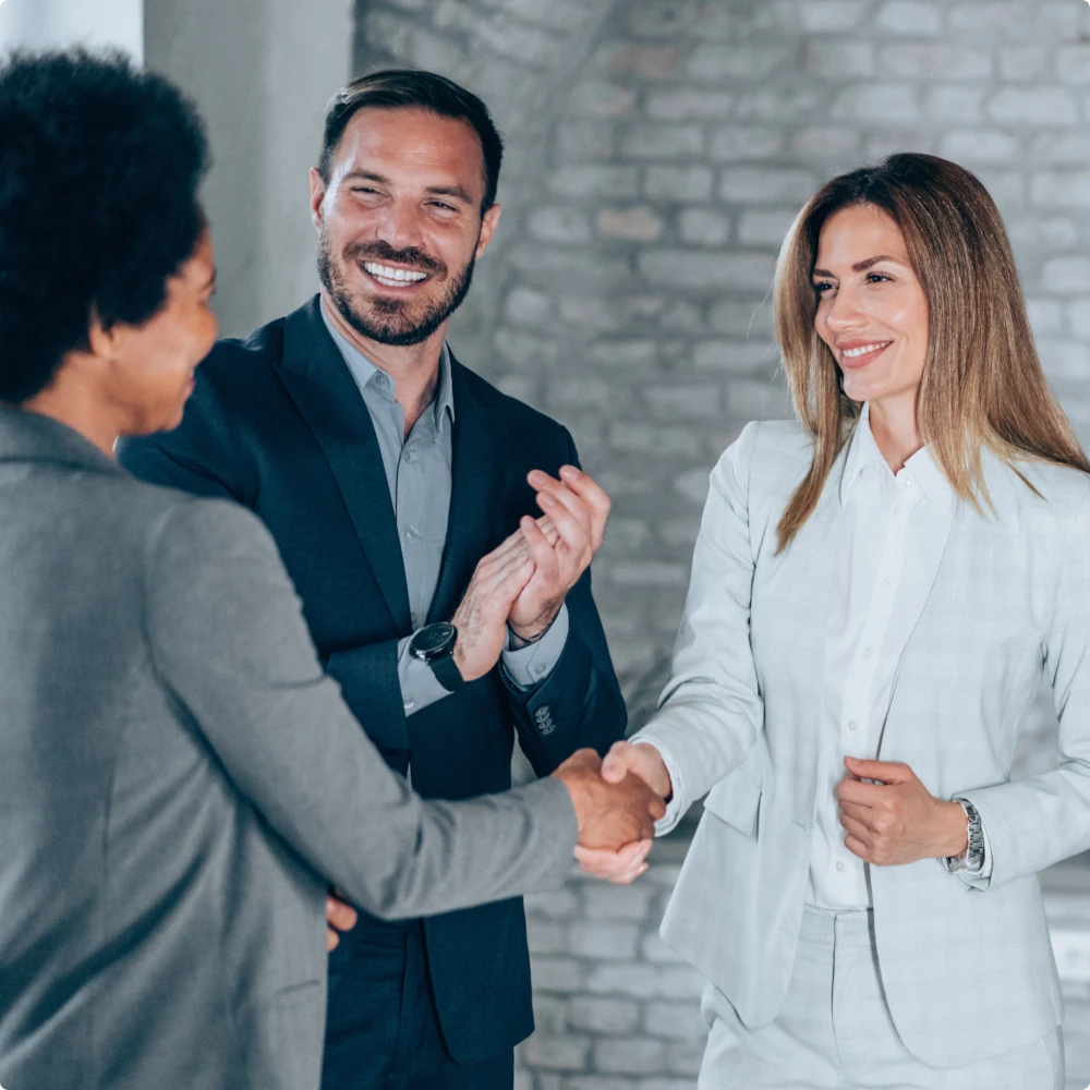 image of three people in a business hallway shaking hands